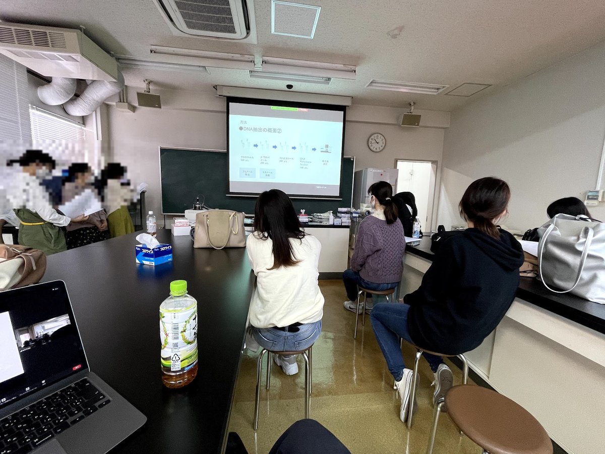 DNA抽出実験の授業風景。スクリーンの手順を見ながら実習室で学ぶ学生たち。